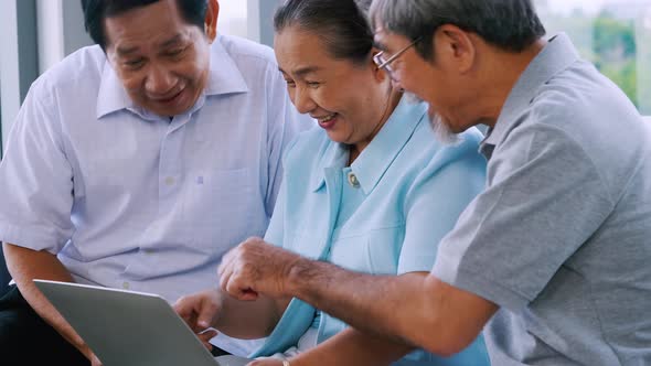 Group of senior friends using laptop together in a retirement home.