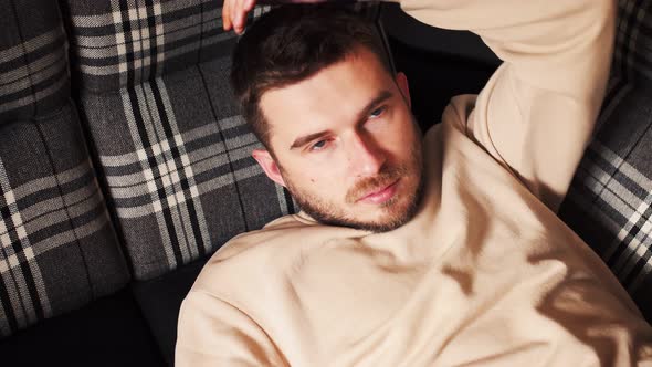 Young Caucasian Man Relaxing on the Couch with Hands Behind Head