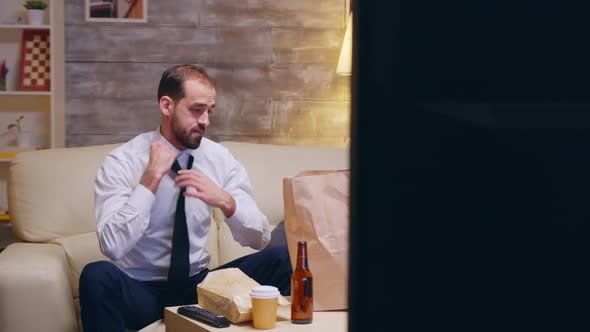 Caucasian Businessman Untying His Tie Sitting on Couch