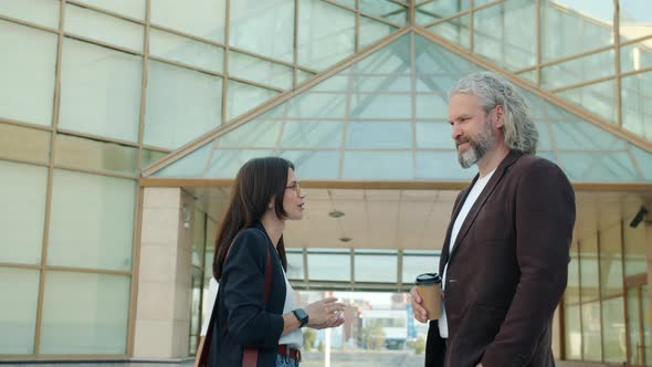 Slow Motion Portrait of Male and Female Business Partners Talking Standing Near Glass Walls Building