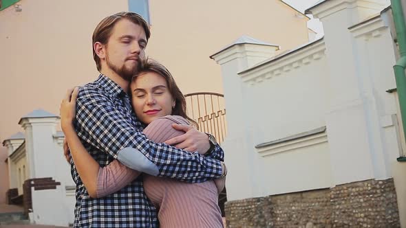 Smiling Boyfriend Standing with Arm Around Girlfriend on Footpath