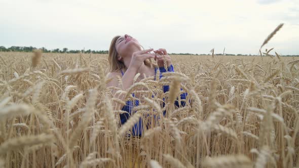 Beautiful Ukrainian Woman Wearing Dress in Ukrainian National Flag Colours Blue and Yellow at Wheat