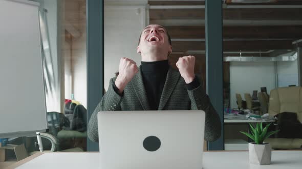 Happy Male Businessman Gets Great News on His Laptop Computer