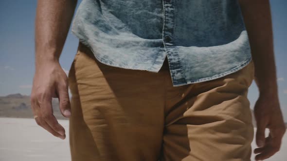 Close-up Camera Tilts Up on Man in Casual Clothes Walking Along Incredible Salt Lake Desert Flats