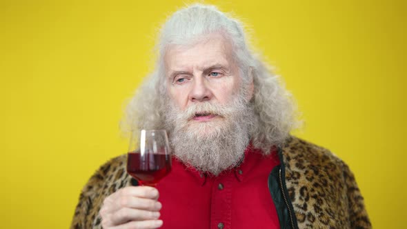 Headshot Portrait of Confident Senior Sommelier Smelling and Tasting Red Wine on Yellow Background