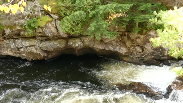 Water swirl creating whirlpool under large rocks forming the river shores