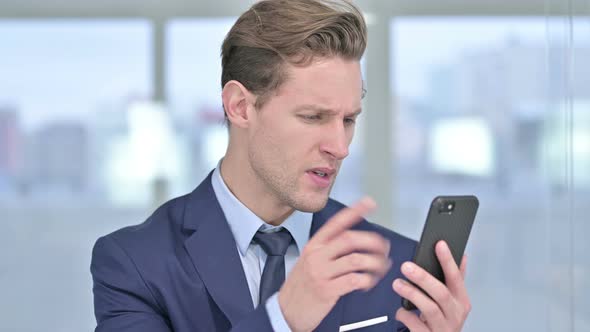 Portrait of Cheerful Young Businessman Celebrating on Smartphone 