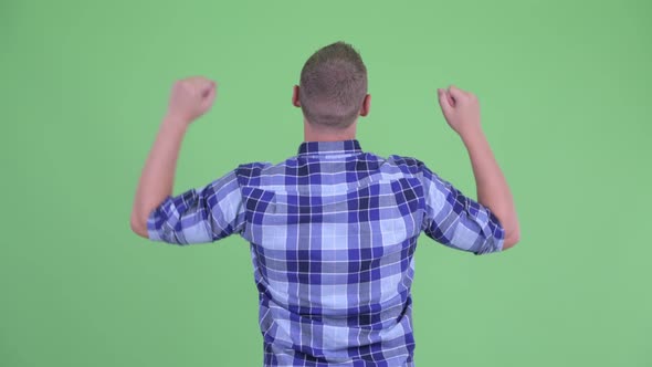 Rear View of Happy Young Hipster Man with Fists Raised