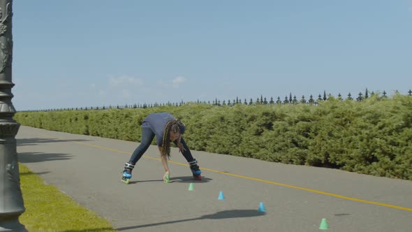 Female Roller Picking Up Cones After Ride Outdoors