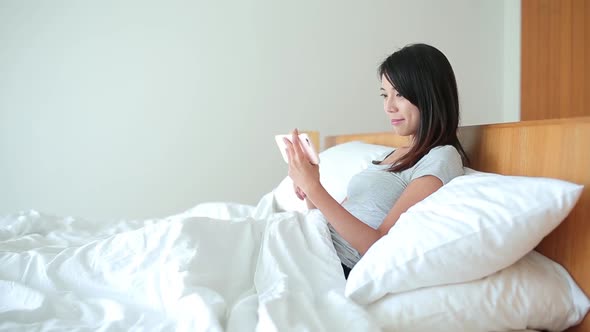 Woman using cellphone on bed