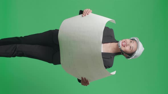 Asian Female Engineer Looking At Blueprint Then Looking Around While Walking On Green Screen