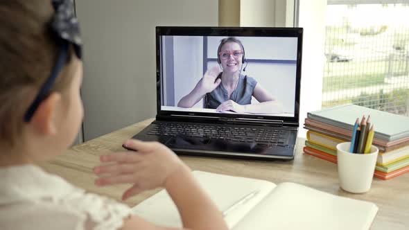 Little Girl Communicates with a Teacher Via the Internet. Online Training During Quarantine.