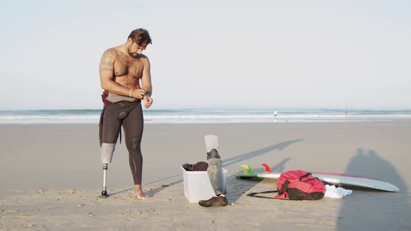 Long Shot of Surfer with Disability Wearing Wetsuit on Beach