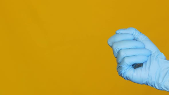 Vaccine against coronavirus Covid-19 in the hand in the glove of a doctor on a yellow background