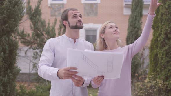 Young Attractive Caucasian Woman Showing Her Client Architectural Drawings and Result of Work