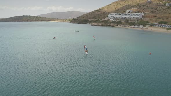 Aerial view of man raises windsurfing sail in the sea in Greece.