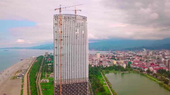 Aerial flight on a drone over construction site with tall tower crane building