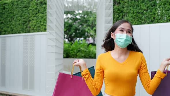 Asian woman wearing face mask. Happy woman with shopping bags