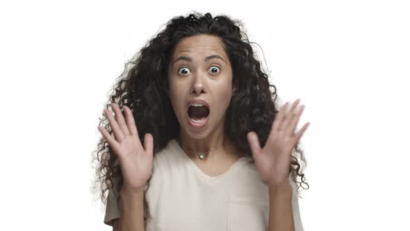 Closeup of Attractive Latino Woman with Curly Long Hair Wearing Beige Tshirt Looking Surprised and