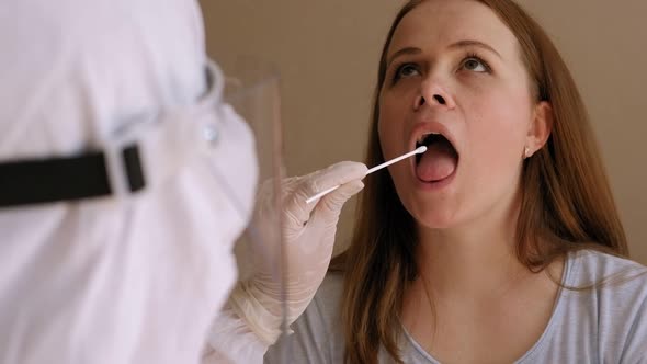 Medical Worker in Protective Suit Taking a Throat Swab for Coronavirus Sample