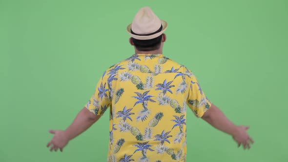 Rear View of Happy Young Overweight Asian Tourist Man with Arms Raised