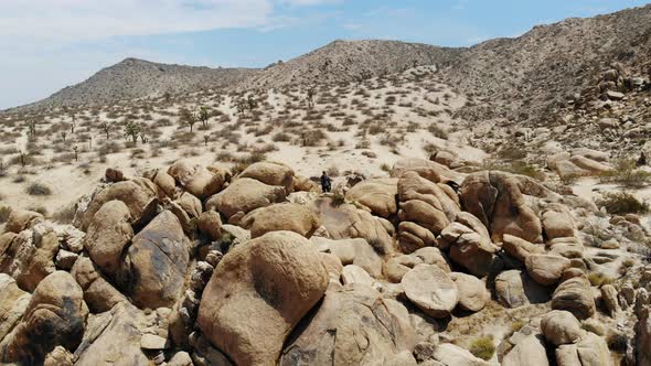 Flying away from a silhouette standing on a large pile of boulders in the middle of a rough desolate