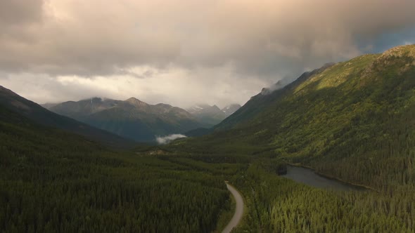 View of Scenic Road Alongside Peaceful Lake Surrounded By Mountains