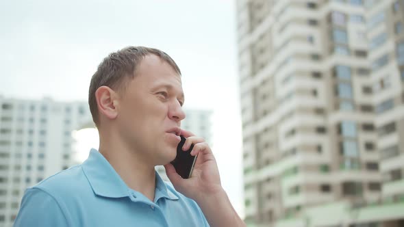 Portrait of a Man Talking on a Mobile Phone Against the Background of Skyscrapers