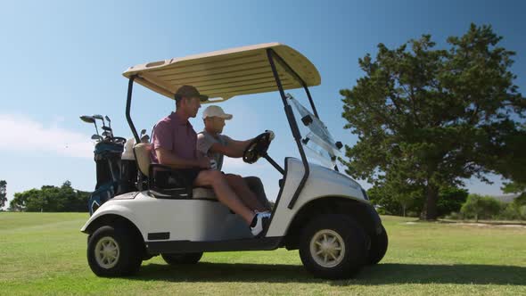 Caucasian male golfers into a golf buggy