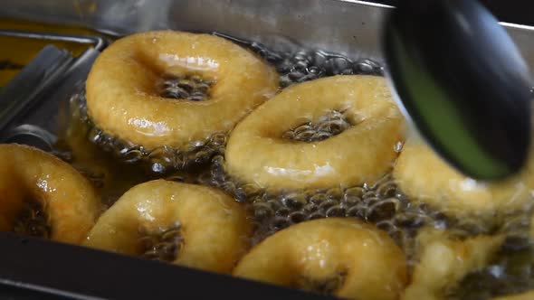 Deep Frying Several Small Round Ring Donuts In Sizzling Oil