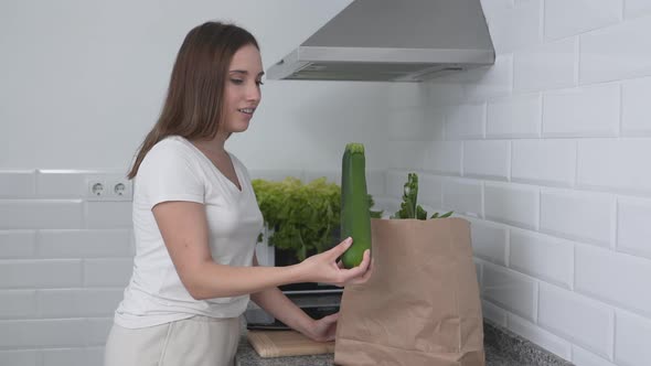 Young Woman Taking Out Fresh Vegetables From Brown Paper Bag