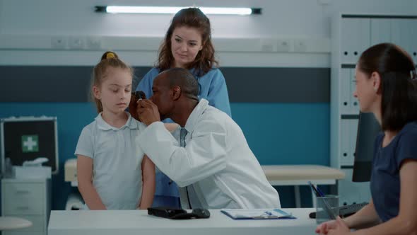 Physician Using Otoscope on Small Child to Do Ear Examination