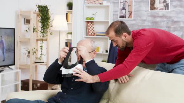 Young Man Learning Old Man How To Use VR Headset