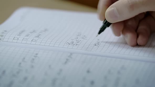 Male Caucasian Hand is Making Notes in a Notebook