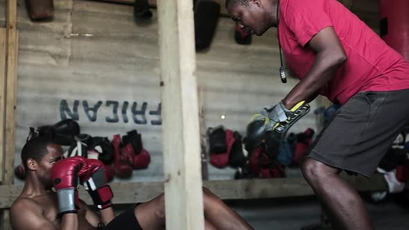 Coach and boxer practicing boxing in the gym