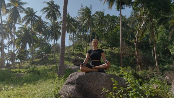 Concentrated Young Sportswoman Practices Yoga on Big Stone in Tropical Rainforest Healthy Lifestyle