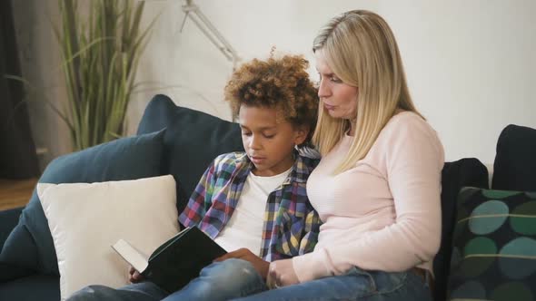 Happy Family Is Reading Together Story From Book Which Holding Little Boy