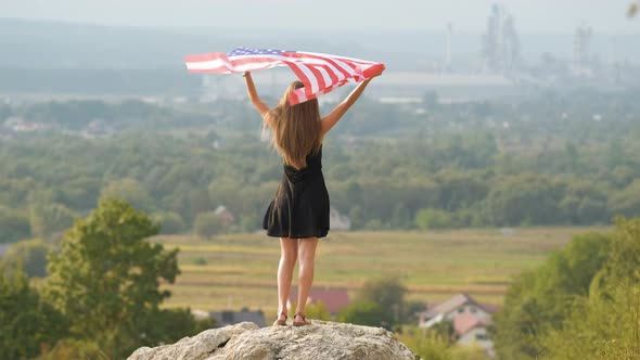 Young Happy American Woman with Long Hair Raising Up Waving on Wind USA National Flag in Her Hands