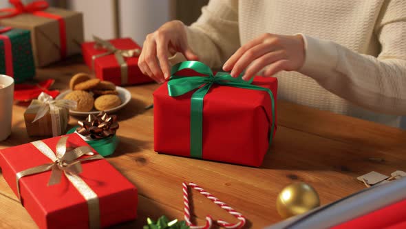 Hands Packing Christmas Gift and Tying Green Bow