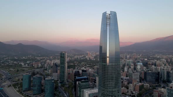 Aerial dolly in of curtain wall Costanera Center skyscraper in modern Sanhattan area, hills in backg