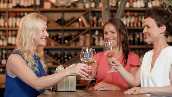 Women Giving Present To Friend at Wine Bar 