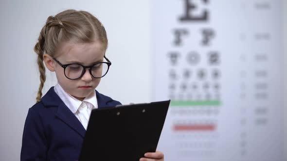 Adorable Child Girl Pretending to Be Eye Doctor, Future Profession Optometrist