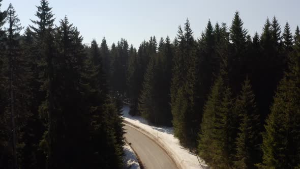 Aerial view of snowy mountain forest with a road
