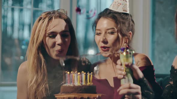 Close Up Portrait of Young Multiracial Female Friends Blowing Out Candles on Birthday Cake and