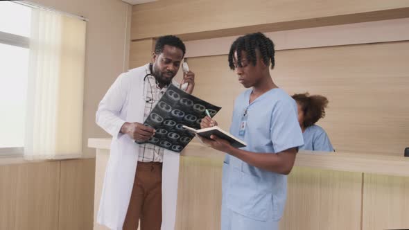 An African American male doctor talks phone at hospital's reception counter.