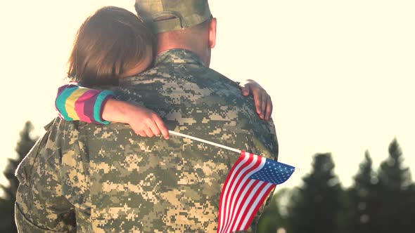 Military Man Hugs Daughter Against Sky Background