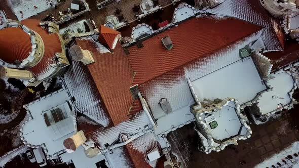Overhead Drone View of Fresh Snow on the Red Tile Roof of a Castle Home. Scenic Aerial Rise Above th