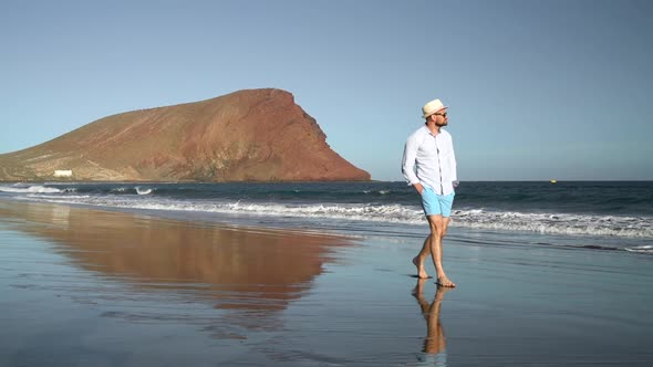 Happy Man Walking Along the Ocean Beach at Sunset