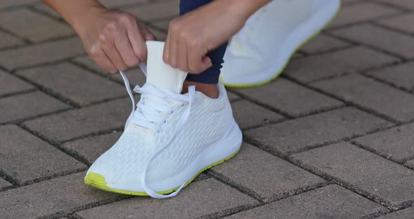 Young adult female tying shoe lace before a run