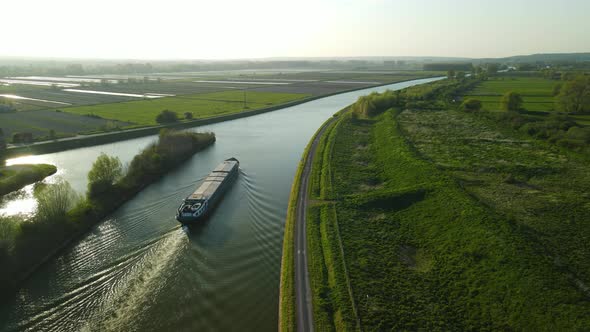 Aerial view in the sunset of a houseboat on a river near Clairmarais, France. There are fields on bo